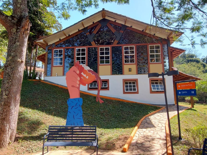 foto com frente do hub.S, casa branca, janelas coloridas, gramado verde